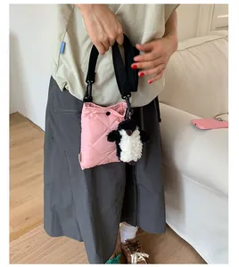 Détail du sac seau matelassé rose avec bandoulière réglable et pendentif pingouin
