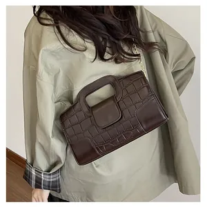 Detail of dark brown faux leather handbag featuring crocodile pattern and gold chain strap