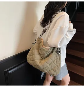 Detail of olive green quilted tote bag with black and white striped scarf shoulder straps