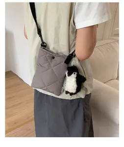 Détail d'un sac bandoulière gris matelassé avec surpiqûres losanges et charm pingouin