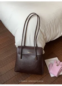 Detail of dark brown leather tote featuring lychee texture and beaded strap accents