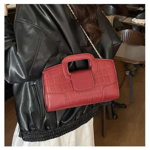 Model wearing red faux crocodile leather handbag with gold chain in a cozy cafe setting