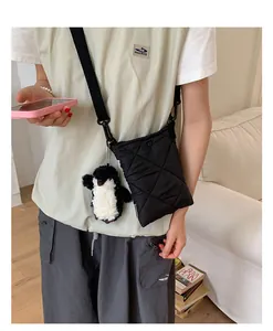 Détail d'un sac bandoulière matelassé noir en nylon avec un charm pingouin en peluche