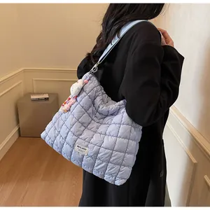 Macro detail of a light blue quilted shoulder bag with decorative charms and brand patch