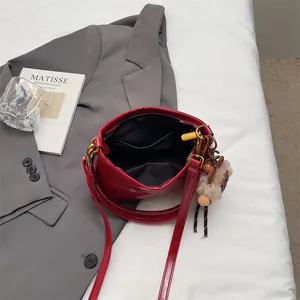 Glossy red faux leather tote bag with gold hardware and brown bear charm on gray blazer