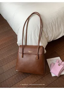 Detail of caramel pebbled leather tote with elegant beaded strap and gold lettering