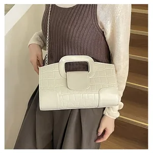 Detail of a minimalist off-white crocodile pattern handbag with golden chain strap
