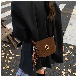 Brown vintage suede crossbody bag with horseshoe buckle and bear charm on back of model