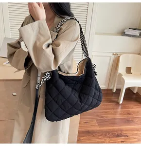 Detail of black quilted hobo bag with striped strap and chic knotted handle design