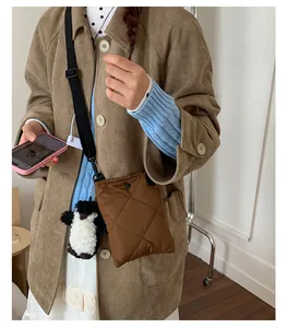 Gros plan d'un sac bandoulière matelassé marron foncé avec un porte-clé pingouin