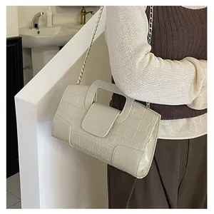Detailed view of cream-white quilted handbag with golden chain strap on a model