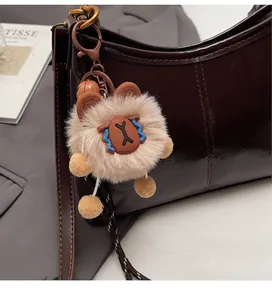 Plush cartoon pendant with soft fur details hanging on a brown leather tote bag