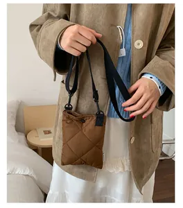 Détail d'un sac seau en nylon matelassé marron avec bandoulière noire réglable et bouton