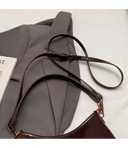 Detail of adjustable long shoulder strap and gold hardware on deep brown tote bag