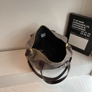 Large gray canvas tote bag with brown leather handles and spacious interior