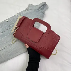 Detail of burgundy crocodile embossed leather handbag with vintage gold chain strap
