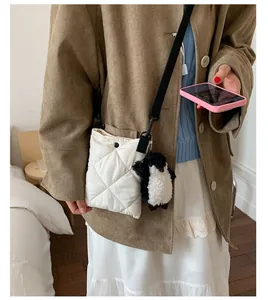 Détail du sac seau matelassé blanc cassé avec un charme de pingouin et bandoulière noire