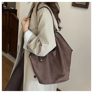 Vue détaillée du grand sac cabas en daim marron foncé avec poignées en cuir et boucles argentées