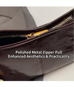 Close-up of smooth gold metal zipper and textured dark brown leather on the tote bag