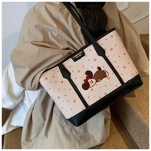 Détail du sac cabas rose à pois avec broderie de chien et plaque de marque métallique élégante