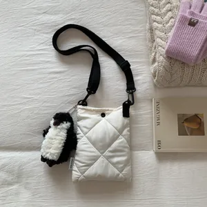 Détail du sac seau matelassé blanc avec bandoulière et breloque pingouin mignonne