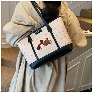 Détail du sac cabas en toile à pois avec broderie de chien et plaque en métal dorée