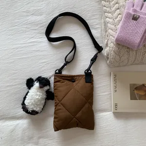 Mini sac seau matelassé marron avec breloque pingouin sur un décor d'automne