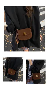 Close-up of brown suede saddle bag with gold horseshoe buckle and tassel detail