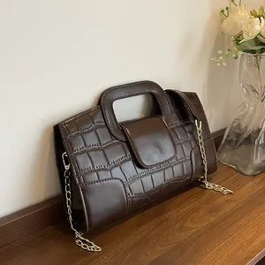 Retro dark brown quilted handbag with crocodile texture and gold chain on wooden table