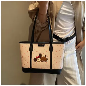 Détail de la broderie ours et finitions en cuir noir sur un cabas en toile beige