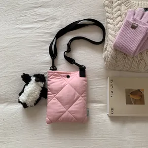Détail du sac seau rose matelassé avec bandoulière réglable noire et breloque de pingouin
