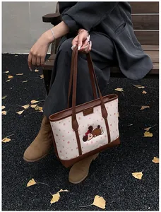 Détail du grand sac cabas à pois avec motif ours posé sur un banc d'automne