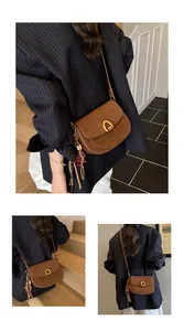 Detail of vintage brown suede crossbody bag with gold horseshoe buckle and beaded tassel