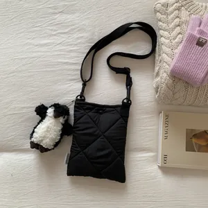 Détail d'un sac bandoulière noir matelassé avec étiquette et breloque pingouin