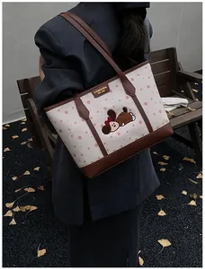 Photo en extérieur d'un cabas en toile beige à pois roses et détails en cuir marron