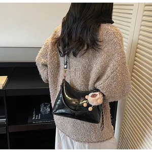 Glossy black hobo shoulder bag with a cute white plush sheep charm detail