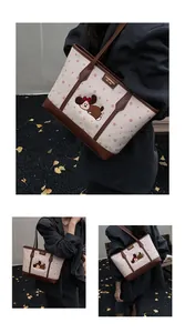 Détail du sac cabas en toile montrant le chiot brodé et les coutures de l'anse en cuir