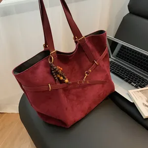 Large burgundy suede tote bag with leather handles and decorative beads in office setting