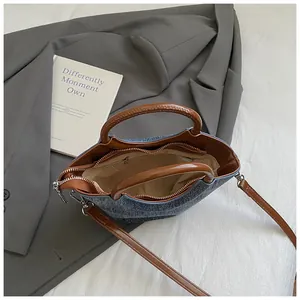 Fashionable denim bucket bag with brown leather handles and a versatile shoulder strap