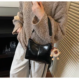 Close-up of black glossy tote bag with soft leather texture and sheep plush pendant charm