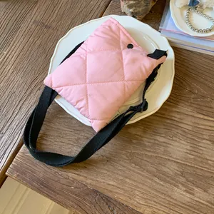 Sac seau rembourré rose matelassé avec sangle noire réglable sur une table en bois avec assiette
