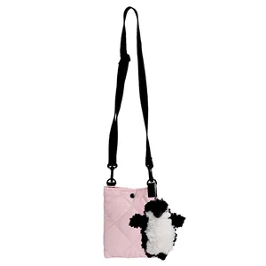 Sac seau matelassé rose avec bandoulière noire et charm pingouin sur fond blanc pur et lumineux