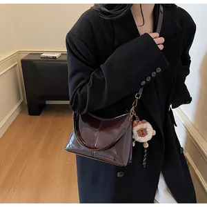 Detail of dark brown glossy leather shoulder bag with a cute alpaca plush keychain