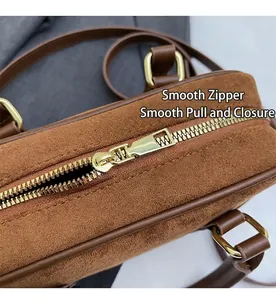 Detail of smooth gold zipper and matte brown suede stitching on bowling handbag