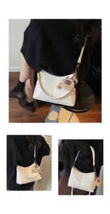 Detail of white patent leather tote bag featuring a cute plush bear charm accessory