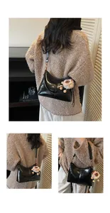 Close-up of black glossy tote bag with soft leather and cute white plush sheep charm