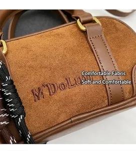 Detailed view of brown suede bowling bag with refined embroidery and woven rope accent