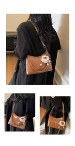 Detail of brown glossy leather tote bag with adjustable strap and plush lion charm