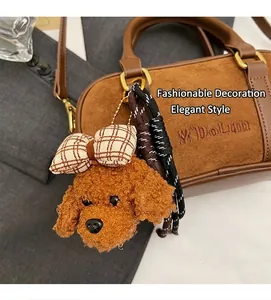Brown plush teddy dog bag charm with plaid bow and braided rope on a handbag