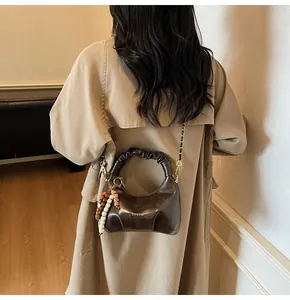 Detail of soft leather pleated tote bag with chain strap and ethnic bead charm